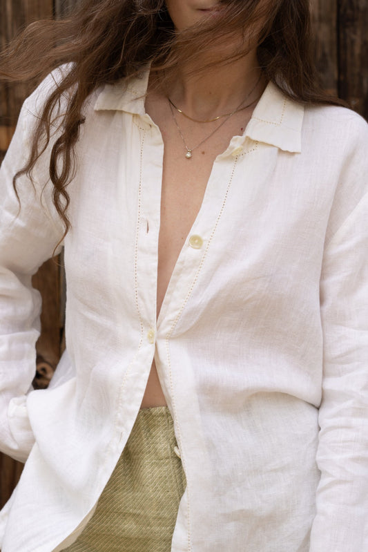 Person wearing a white button-up shirt with a wooden background